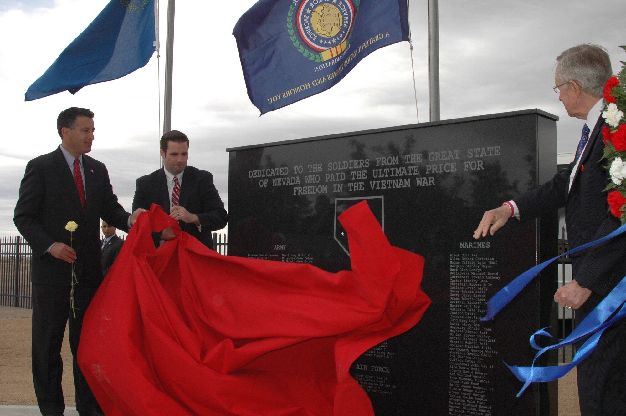 From left, Nevada Gov. Brian Sandoval, the commander-in-chief of the Nevada Guard, Caleb Cage, the executive director of the Nevada Office of Veterans Services, and Majority Leader Sen. Harry Reid unveil the Vietnam War Memorial Wall at the Northern Nevada Veterans Memorial Cemetery on May 27 in Fernley, Nev.  NV ARNG photo by Sergeant 1st Class Erik Studenicka (released).