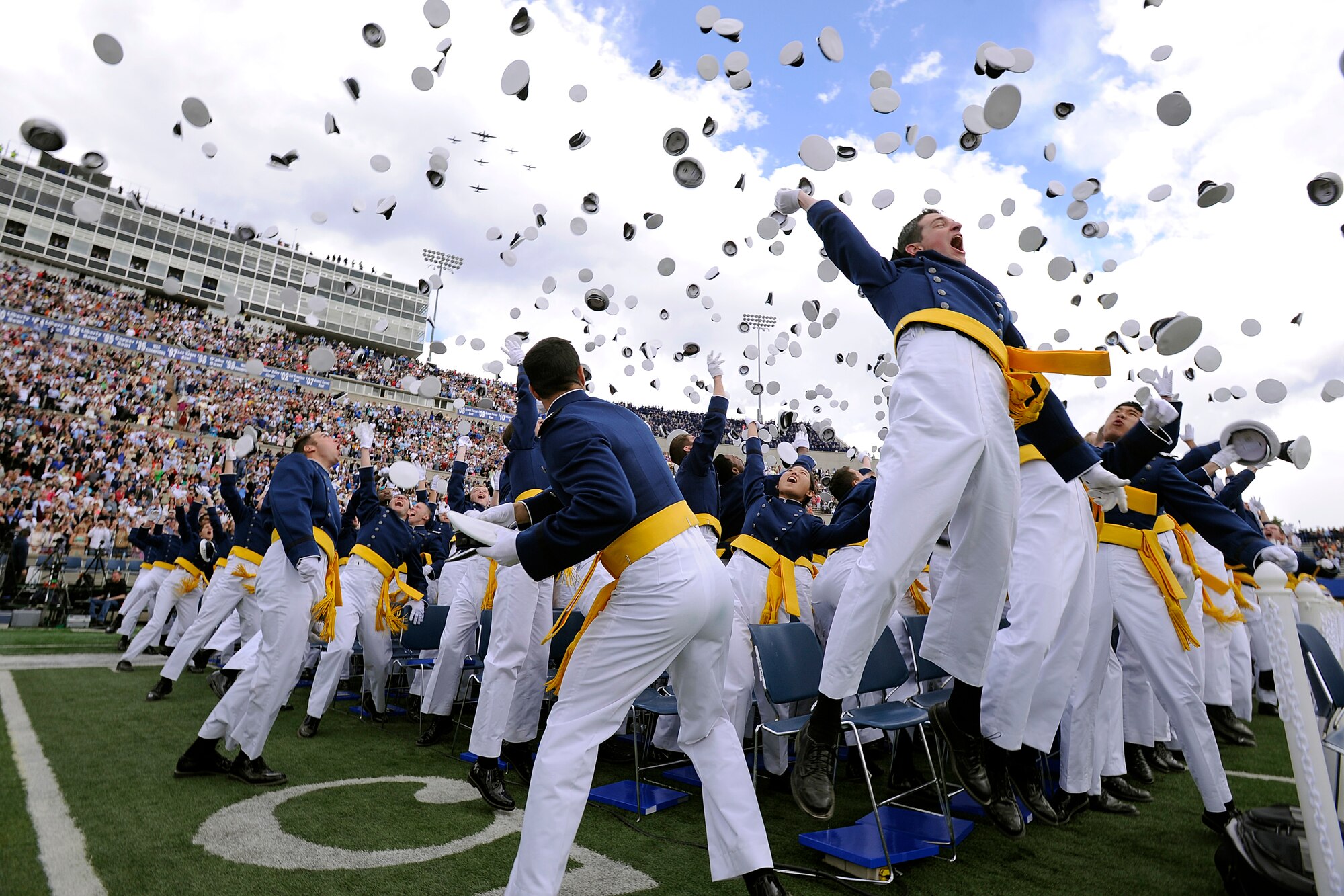 The 1,024 newly minted 2nd Lieutenants of the U.S. Air Force Academy Class of 2013 toss their hats in the air as the Texas Flying Legends Museum, based out of Ellington Field, Texas provide graduation ceremony fly-by support at the Academy's Falcon Field in Colorado Springs, Colo. May 29, 2013. (U.S. Air Force Photo by Mike Kaplan/Released)