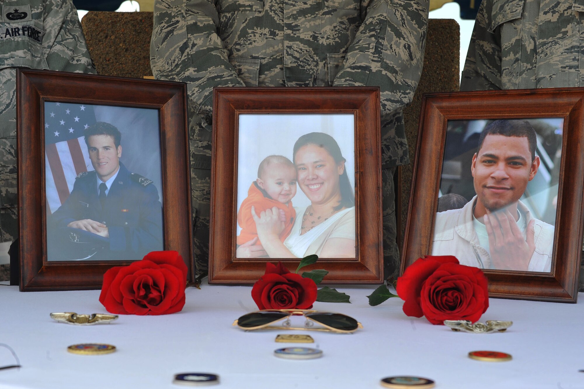 Photos of Capt. Mark Tyler Voss, Capt. Victoria A. Pinckery and Tech. Sgt. Herman “Tre” Mackey, III sit among a table of mementos at the Shell 77 Memorial Service at McConnell Air Force Base, Kan., May 28, 2013. The Airmen were deployed to the 376th Air Expeditionary Wing's 22nd Expeditionary Air Refueling Squadron in support of Operation Enduring Freedom during the time their KC-135 Stratotanker tragically crashed, May 3 in Kyrgyzstan. (U.S. Air Force photo/ Staff Sgt. Jess Lockoski)