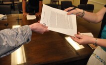 A federal employee assigned to the 512th Airlift Wing, Dover Air Force Base, Del., turns in the notice of proposed furlough she received May 29, 2013. The Reserve wing’s 250 civilian employees received a copy of the memorandum for themselves after signing and returning the original notification to wing leadership. (U.S. Air Force photo/Master Sgt. Veronica Aceveda)   