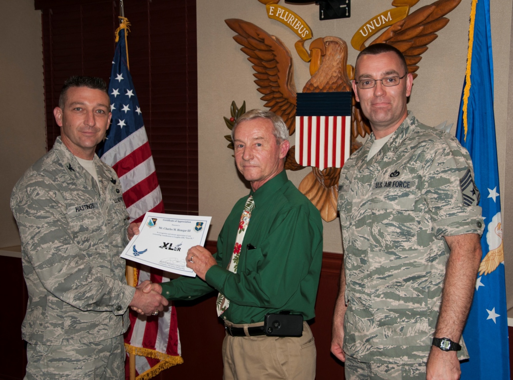 Charles Henegar III, 47th Student Squadron T-1A Jayhawk simulator instructor, poses with Col. Brian Hastings, 47th Flying Training Wing commander, and Chief Master Sgt. Garry Berry, 47th FTW command chief, after being presented the XLer of the week award at Laughlin Air Force Base, Texas, May 14, 2013. The XLer is a weekly award chosen by wing leadership and given to those who consistently make outstanding contributions to Laughlin and their unit. (U.S. Air Force photo/Joel Langton)