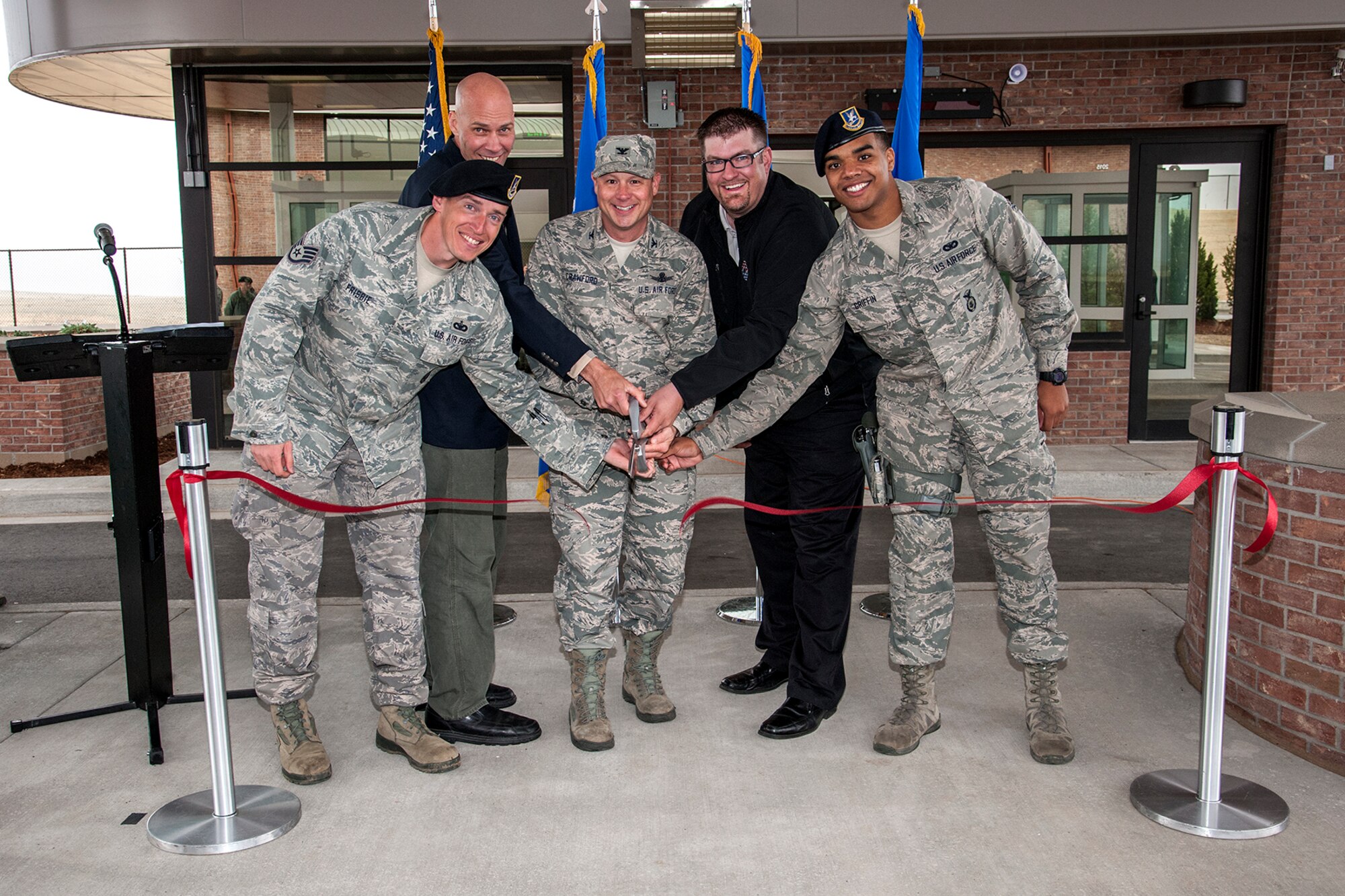 PETERSON AIR FORCE BASE, Colo. -- (Left to right) Staff Sgt. Keith Frisbie, 21st Security Forces Squadron; Brian Dziekonski, U. S. Army Corps of Engineers; Col. Chris Crawford, 21st Space Wing commander; Scott Amhaus, Komada LLC; and Airman 1st Class Marcus Griffin, 21st SFS, cut the ribbon May 23 celebrating the completion of the new east gate. The gate was constructed to improve vehicle flow onto and off of base, and includes a larger commercial vehicle search area. The east gate hours remain 5 a.m.-10 p.m. daily. (U.S. Air Force photo/Craig Denton)