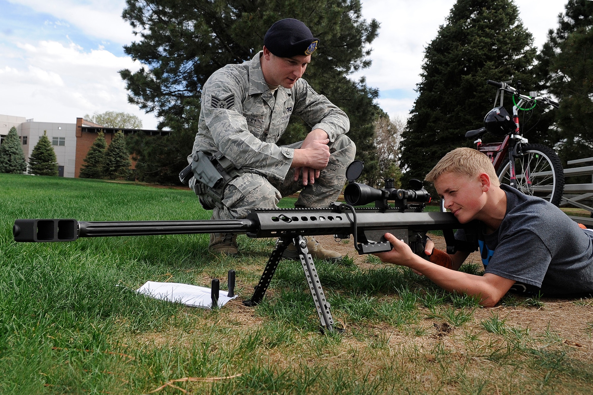 PETERSON AIR FORCE BASE, Colo. – Staff Sgt. Timothy Dailey, 21st Security Forces Squadron, directs Hunter Edder as he targets an imaginary foe with an M107 long range sniper rifle May 17 at Patriot Park. Edder inspected many of the weapons at the 21st SFS military working dog and firearms demonstration at Patriot Park, part of the squadron’s police week activities. (U.S. Air Force photo/Rob L. Bussard)