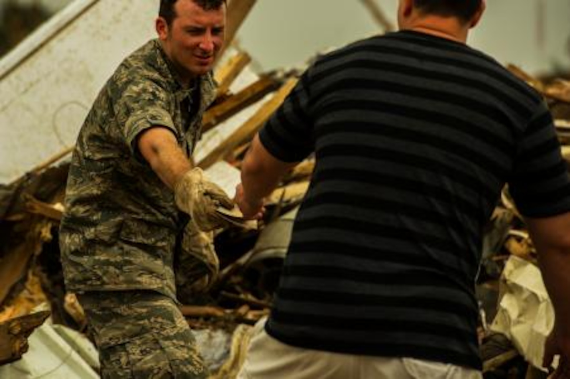 Capt. Ryan Gers, gives a homeowner family photos he uncovered, May 24, 2013, in the debris of a home leveled by a May 20 tornado that ripped through parts of Moore, Okla. More than 600 airmen from the greater Oklahoma area volunteered to assist in the relief efforts. Gers is assigned to the 965th Airborne Air Control Squadron, Tinker Air Force Base, Okla., and hails from Scottsdale, Ariz. (U.S. Air Force photo by Staff Sgt. Jonathan Snyder)