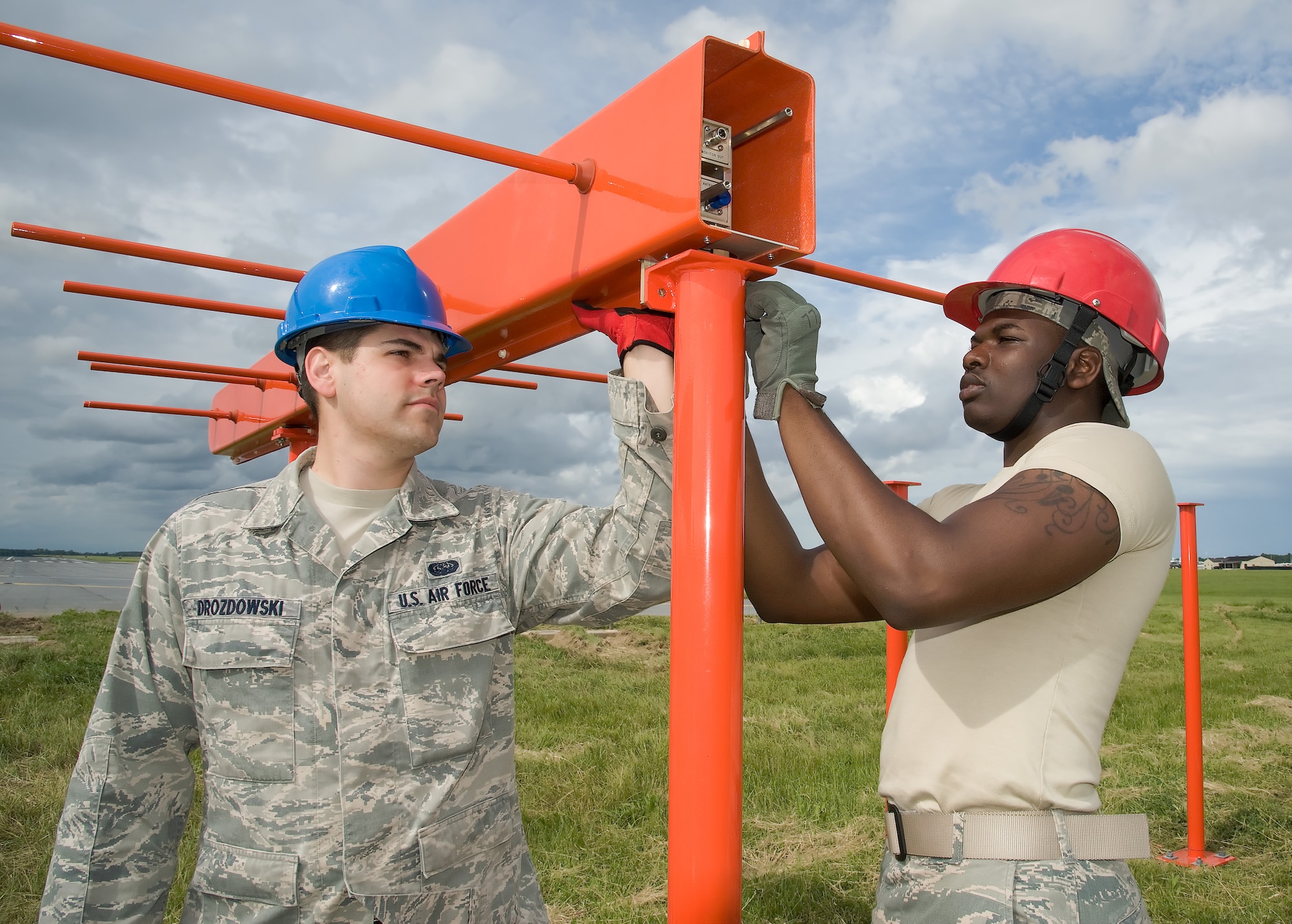 Airman 1st Class Michael Drozdowski (left) and A1C Jonathan Gary, 436th Communications Squadron, work together to install bolts on an instrument landing system (ILS) antenna at the approach end of runway 01 at Dover Air Force base on May 23, 2013 at Dover Air Force Base, Del. (U.S. Air Force photo/Greg L. Davis)