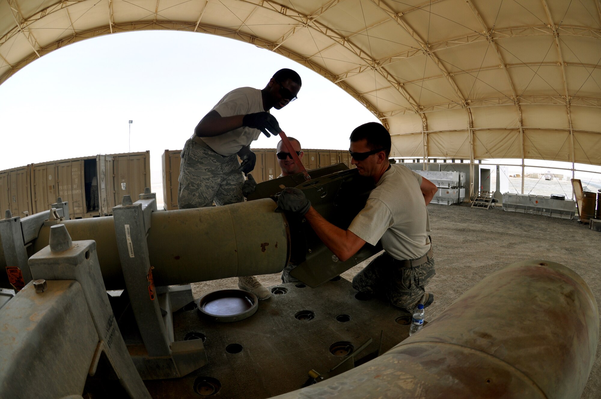 U.S. Air Force Staff Sgts. Arryn Meneese, top left, Michael Maley, center, and Jason Peay, left, all conventional munitions maintenance crew chiefs, install the fin to the Guided Bomb Unit-28 on May 22, 2013. The GBU-28 is a 5,000 pound laser-guided conventional munition. (U.S. Air Force photo by Staff Sgt. Timothy Boyer)      