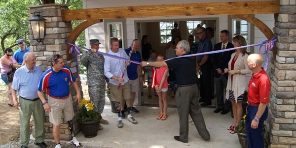 Veteran Robert Jackson, who lost both his legs while serving in Afghanistan in 2003, cuts the ribbon at the Folds of Honor Cottage at CrossTimbers Marina at Skiatook Lake. The May 26 ceremony marks the completion of construction on the retreat dedicated to the exclusive and cost free use of veterans served by the Folds of Honor Foundation.