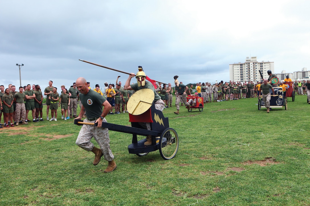Marines and sailors compete in a chariot race May 24 during the 3rd Marine Logistics Group 55th anniversary celebration at Camp Kinser. Marines and sailors competed in various events at the field meet, such as pugil stick bouts, obstacle course relays, a tug-of-war challenge and volleyball tournament. The Marines and sailors are with 3rd MLG, III Marine Expeditionary Force. Photo by Lance Cpl. Jose D. Lujano