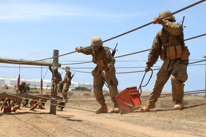 Recruits of Company M, 3rd Recruit Training Battalion, work together to carry a large ammo can across a rope during the Crucible confidence course at Edson Range aboard Marine Corps Base Camp Pendleton, Calif. May 21.  Communication and teamwork are some of the key tools recruits must utilize for them to navigate the various obstacles.  (U.S. Marine Corps photo by Lance Cpl. Benjamin E. Woodle/Released)