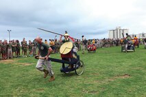 Marines and sailors compete in a chariot race May 24 during the 3rd Marine Logistics Group 55th anniversary celebration at Camp Kinser. Marines and sailors competed in various events at the field meet, such as pugil stick bouts, obstacle course relays, a tug-of-war challenge and volleyball tournament. The Marines and sailors are with 3rd MLG, III Marine Expeditionary Force.