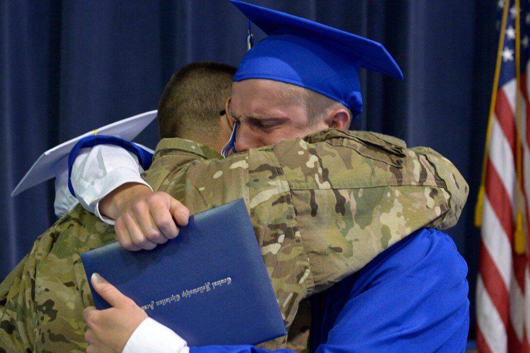 Maj. Jason Moll embraces his son, Taylor, after returning from deployment and surprising him at his graduation. (U.S. Air Force photo by Raymond Crayton/Released)