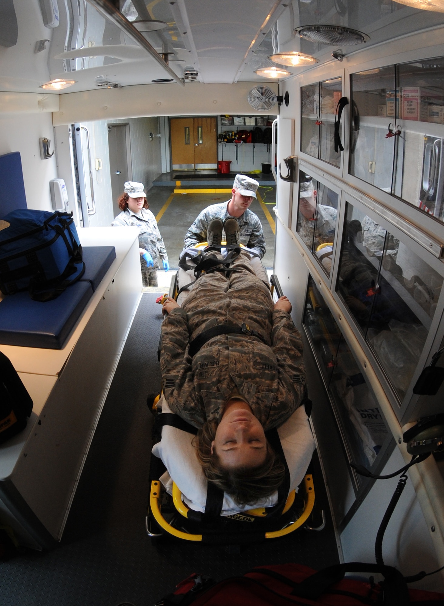 Senior Airman Blair Brakebill and Airman 1st Class Dillon Cobb, 509th Medical Operations Squadron ambulance services technicians, simulate placing a patient on a stretcher at Whiteman Air Force Base, Mo., May 29, 2013. Ambulance service technicians constantly train to ensure they are mission ready and fully qualified to complete the job. (U.S. Air Force photo by Airman 1st Class Bryan Crane/Released)