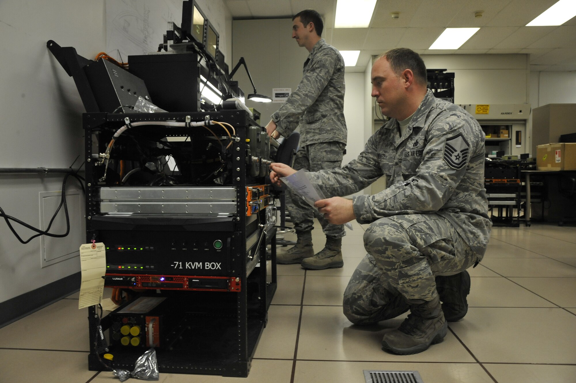 1st Lt. Andrew Klausner, 509th Maintenance Operations Squadron flight commander, and Master Sgt. Michael White, 509th MOS B-2 Spirit computer-aided design manager, perform an adaptable communications suite check on the Defense Advanced GPS Receiver at Whiteman Air Force Base, Mo., May 15, 2013. White is programming the DAGR for operation with the communications suite. (U.S. Air Force photo by Airman 1st Class Keenan Berry/Released)
