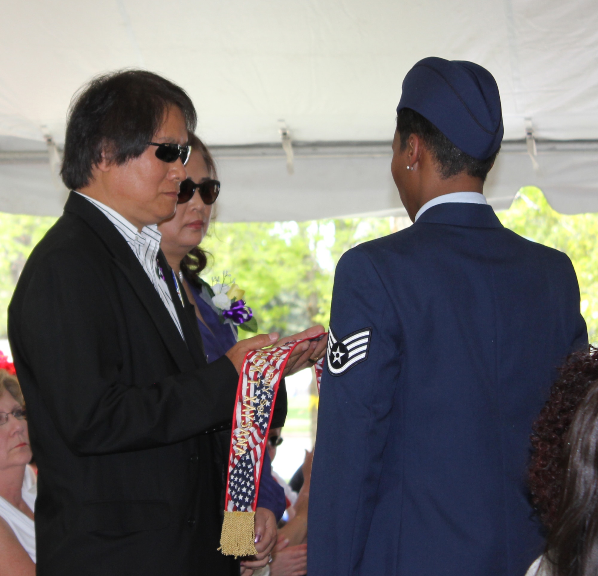 Staff Sgt. Letitia Edwards presents a tribute banner to Mr. and Mrs. Thong Xaysana of Westminster in remembrance of their son Army Sgt. Vorafack Thomas Xaysana who was killed in Iraq in 2011 as part of the Veterans Memorial Day Tribute in Denver, May 25. (U.S. Air Force photo/Cindy Dewey) 