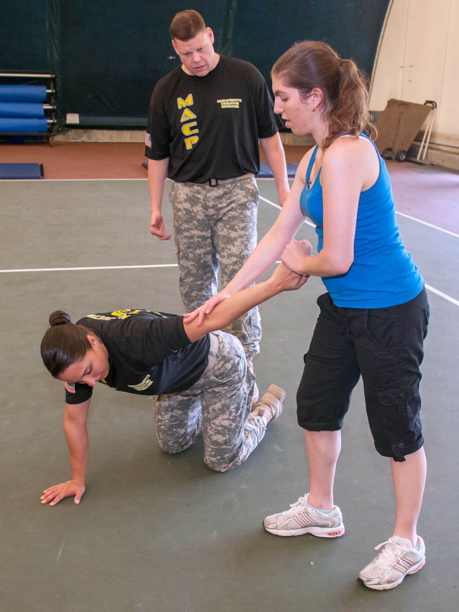 HANSCOM AIR FORCE BASE, Mass. -- Alexis Zallas practices a self-defense technique on Sgt. Brandi Walsh under the supervision of Army Staff Sgt. Chris Walton during a Women's Self-Defense Seminar in the Tennis Bubble May 28. Walsh and Walton, Mass. National Guard Modern Army Combative Program level three and level four instructors respectively, provided techniques to women so they can safeguard themselves during a potential sexual assault either as an active bystander or basic self-defense. The seminar was an extension of Sexual Assault Awareness Month that took place in April. (U.S. Air Force photo by Rick Berry)