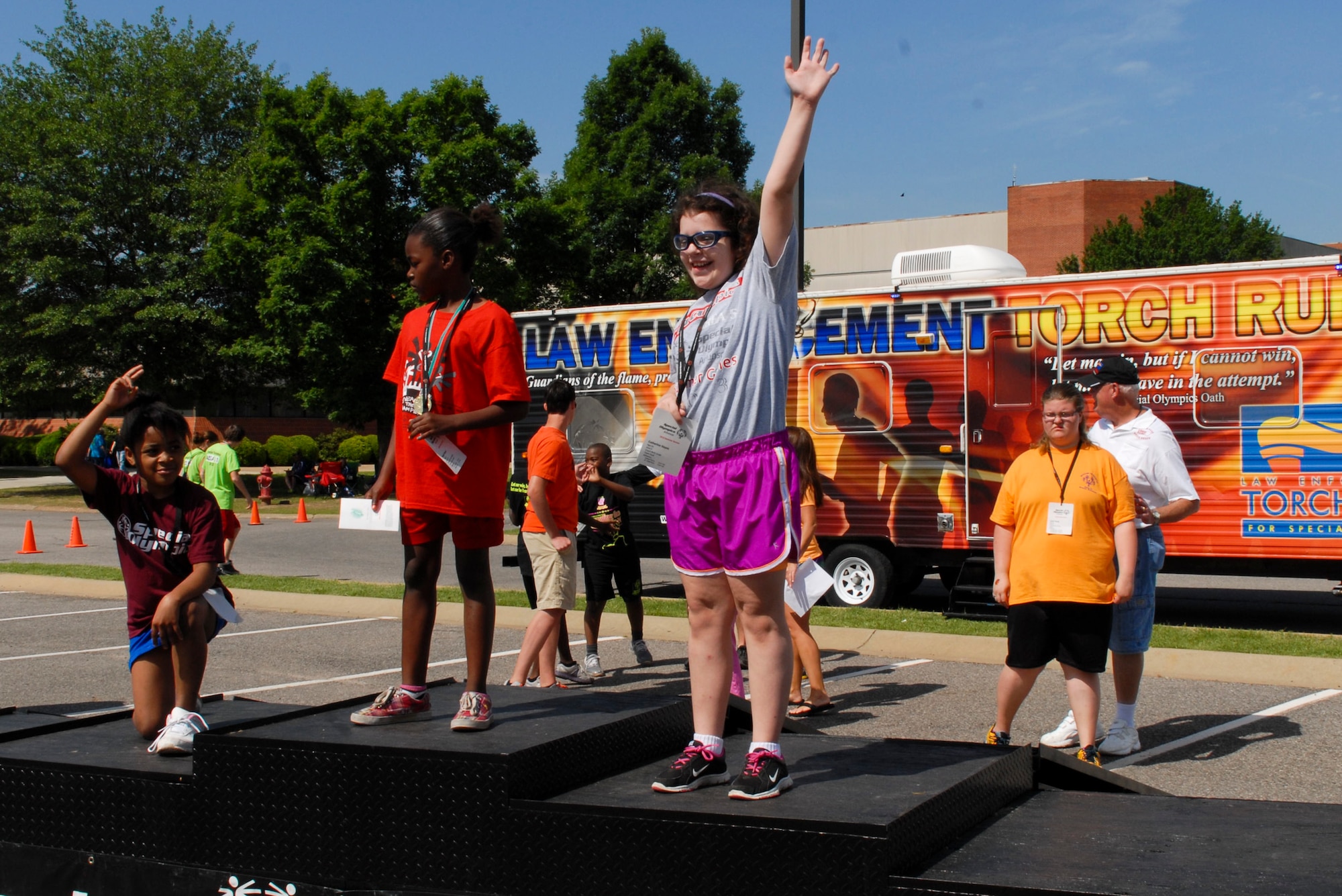 Catherine Hayes, daughter of Michael and Stephanie Hayes, celebrates on the podium at the 2013 Arkansas Summer Special Olympics May 25, 2013, at Harding University in Searcy, Ark. Hayes won the bronze medal in the 100 meter dash and also won a silver medal for the softball throw. (U.S. Air Force photo by Staff Sgt. Jacob Barreiro)