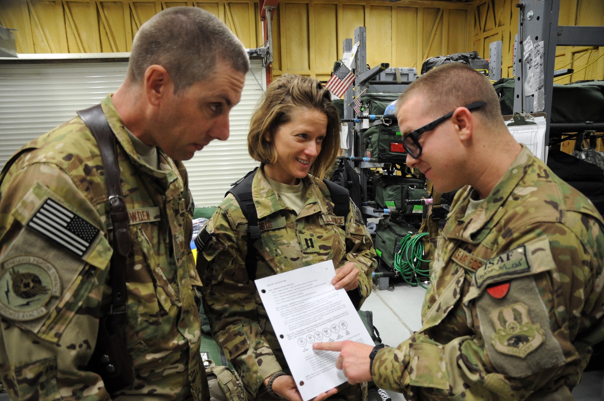Tech. Sgt. Abraham Lowden, 455th Expeditionary Aeromedical Evacuation Squadron medical technician, and Capt. Andrea Essig, 455th EAES flight nurse, discuss the Wong-Baker faces pain rating scale with Airman 1st Class Adam Heil on Bagram Airfield, Afghanistan, May 29, 2013. Essig and Lowden used this nonverbal tool recently while transporting an injured Afghan boy who did not speak English. (U.S. Air Force photo/Staff Sgt. David Dobrydney)