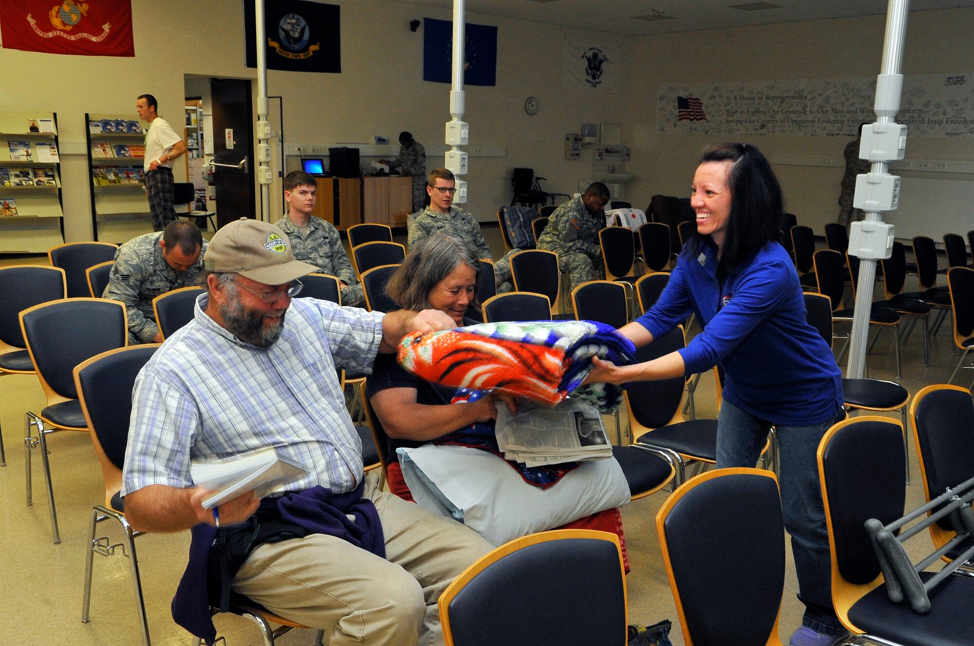 Alicia Green, Contingency Aeromedical Staging Facility USO information specialist, hands a quilt to a patient’s father, May 28, 2013, Ramstein Air Base, Germany. The CASF USO offers a home away from home for wounded service members in transit from combat zones to the U.S. The CASF USO has a variety of employees and volunteers who provide support to the wounded warriors. (U.S. Air Force photo/Airman 1st Class Trevor Rhynes)