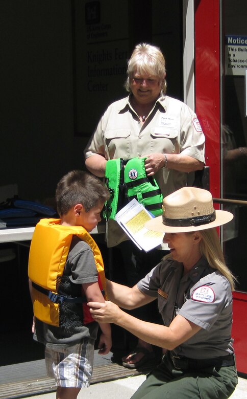 Park Host Volunteer Susan Fehr, top, looks on as Ranger Heather Wright fits a young man with a brand new life jacket during Life Jacket Trade-in Day, May 24, at Stanislaus River Parks, the U.S. Army Corps of Engineers Sacramento District park at Knights Ferry, Calif. Sponsored by the California Department of Boating and Waterways, the exchange offered a new life jacket in return for any used life jacket.