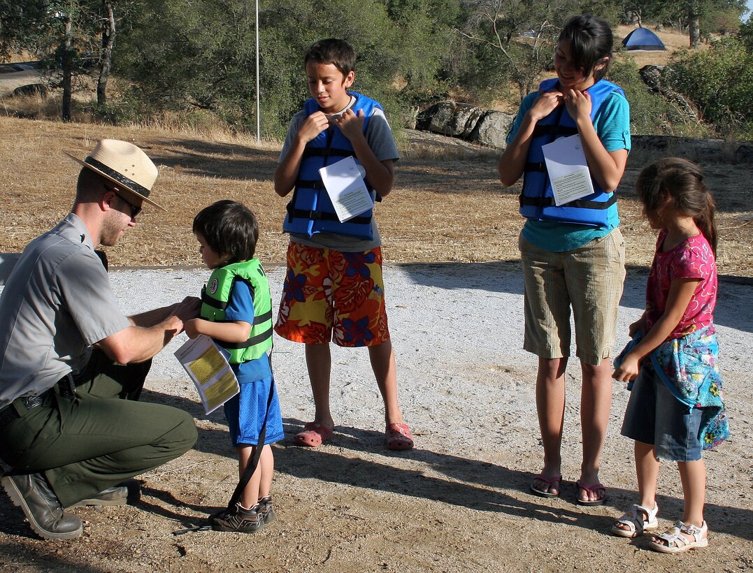 Andy Steele, park ranger, presents a brand new life jacket in trade for a used item during Life Jacket Trade-in Day, May 24, at the U.S. Army Corps of Engineers Sacramento District facility at Eastman Lake, Raymond, Calif. The life jacket exchange was sponsored by the California Department of Boating and Waterways. 