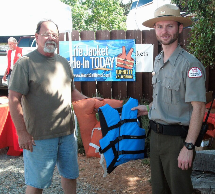 Kevin Franken, park ranger at the U.S. Army Corps of Engineers Sacramento District facility at New Hogan Lake, presents a brand new life jacket in trade for a used item during Life Jacket Trade-in Day, May 24. The event was sponsored by the California Department of Boating and Waterways.