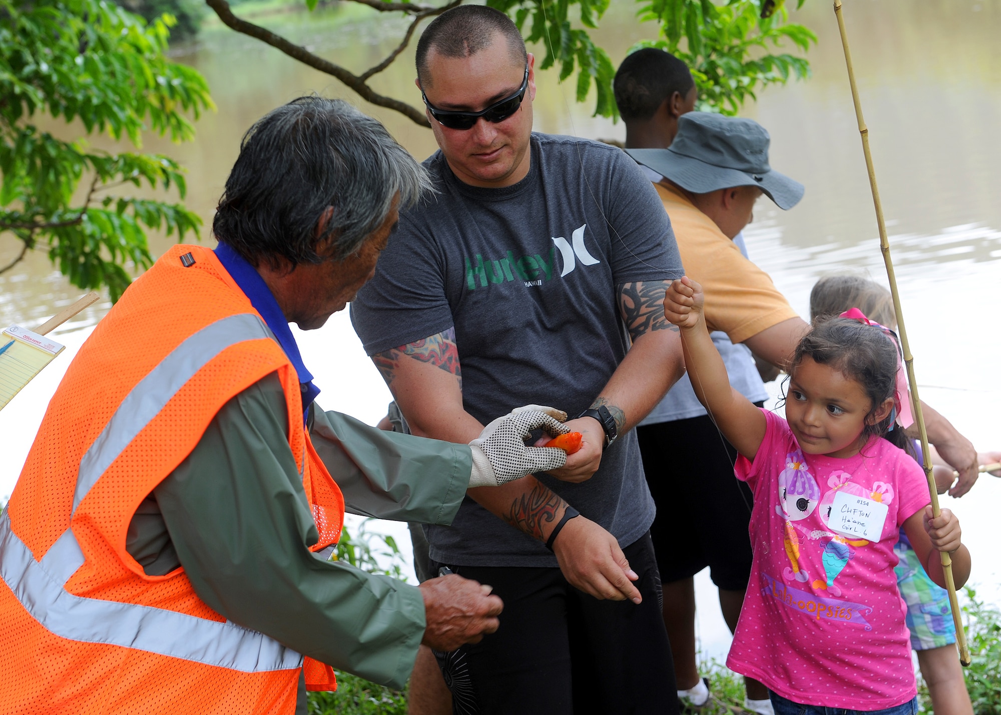Ha’ane Clifton, 6, left, and her father  Tech. Sgt. Austin Clifton, 647th Security Forces, Squadron, non-commissioned officer in charge commander support staff, shows off her catch to a volunteer fishing marshal at the 2013 Keiki Fishing Tournament at Ho'omaluhia Botanical Gardens in Kaneohe, Hawaii, May 29, 2013. The fishing tournament was sponsored by the Friends of Hickam, a group of community leaders who facilitate between the 15th Wing at Joint Base Pearl Harbor-Hickam, Hawaii, and the Hawaii community seeking to support, promote, and foster stronger community relations with those associated with the 15th Wing. (U.S. Air Force photo Tech. Sgt.  Jerome S. Tayborn)