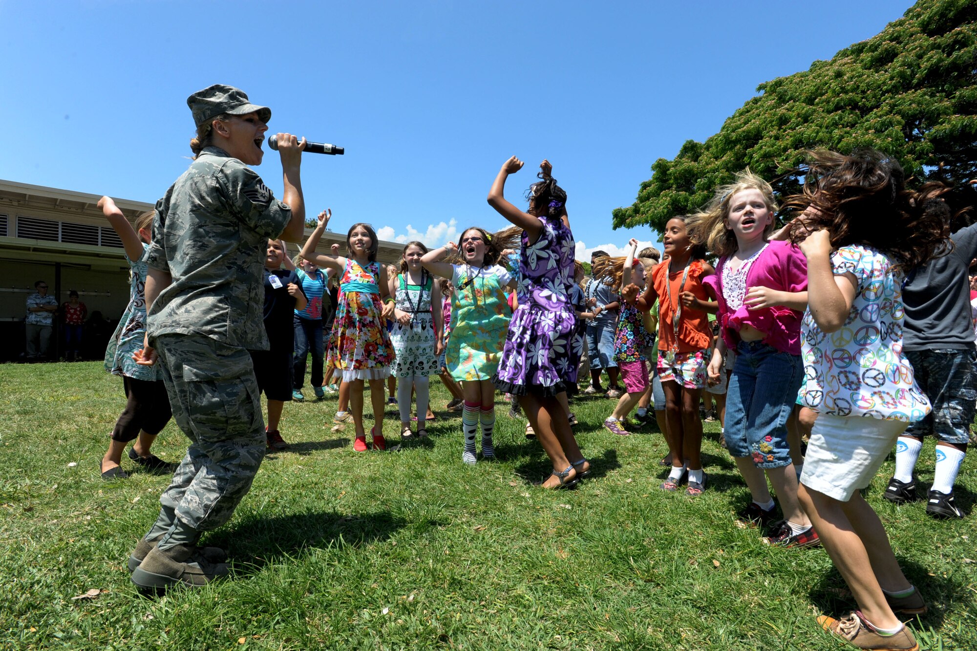 JOINT BASE PEARL HARBOR-HICKAM, Hawaii -- Staff Sgt. Courtney Clifford, a vocalist with the United States Band of the Pacific - Hawaii Hana Hou! Ensemble, joins a group of energetic girls here while she continues to sing with the band at the Hickam Elementary School performance, May 22, 2013. The United States Band of the Pacific – Hawaii has many performances scheduled during the summer. (U.S. Air Force photo by Dakota Chance)