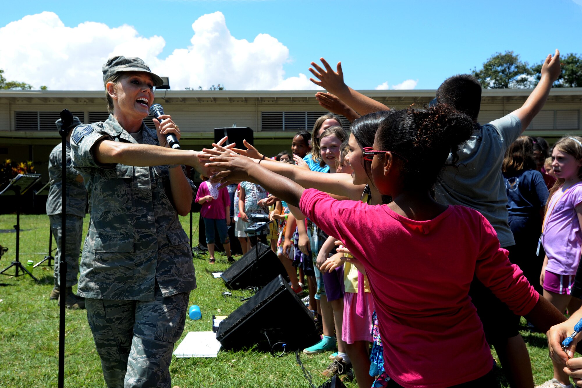 JOINT BASE PEARL HARBOR-HICKAM, Hawaii -- Master Sgt. Lara Murdzia , a vocalist with the United States Band of the Pacific – Hawaii Hana Hou! Ensemble, walks the front row of Hickam Elementary students as they reach to touch her hand at the band’s performance at Hickam Elementary School here, May 22, 2013. The group performed with the students to celebrate the end of the school year. (U.S. Air Force photo by Dakota Chance)