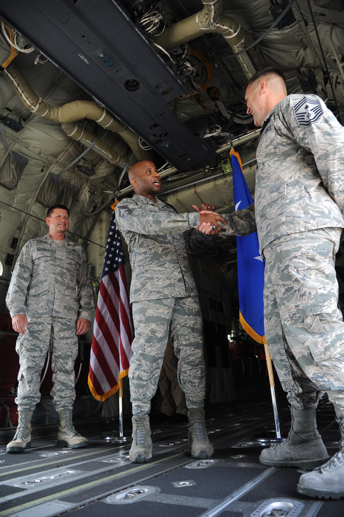 Maj. Gen. Leonard Patrick, 2nd Air Force commander, watches as Chief Master Sgt. Edward Bradley III, 2nd AF military training career field manager, congratulates Chief Master Sgt. Deno Mackin, 2nd AF command chief, after they both completed the U.S. Armed Forces oath of enlistment during a reenlistment ceremony May 31, 2013, inside a C-130J aircraft at Keesler Air Force Base, Miss. Together they’ve dedicated more than 56 years of military service.  (U.S. Air Force photo by Kemberly Groue)