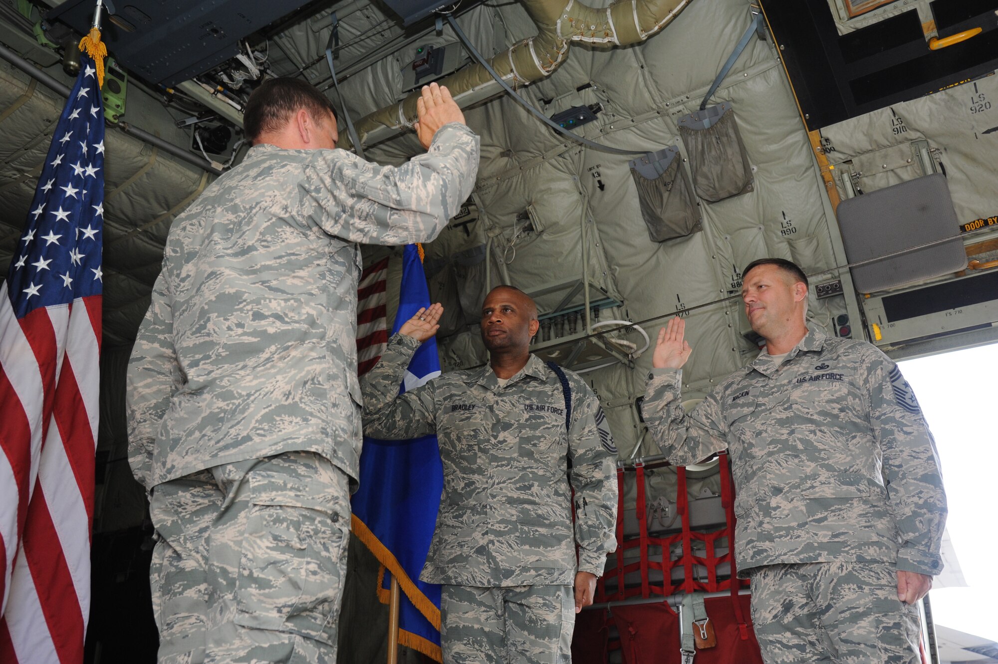 Maj. Gen. Leonard Patrick, 2nd Air Force commander, prepares to reenlist Chief Master Sgts. Edward Bradley III, 2nd AF military training career field manager, and Deno Mackin, 2nd AF command chief, during a reenlistment ceremony May 31, 2013,inside a C-130J aircraft at Keesler Air Force Base, Miss.  Together they have dedicated over 56 years of military service. Together they’ve dedicated more than 56 years of military service.  (U.S. Air Force photo by Kemberly Groue)