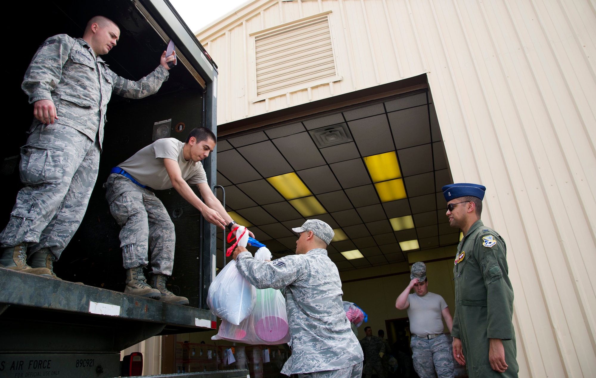 Senior Airman Walter Bolles, an air crew flight equipment specialist with the 552nd Operations Support Squadron,  passes donated relief supplies to Senior Airman John Sloop, with the 32nd Combat Communications Squadron, on May 23. The donated supplies were flown in from Davis-Monthan Air Force Base, Ariz., after a tornado with winds ranging from 200 to 210 mph struck Moore on May 20, 2013. Airman Bolles is originally from Bremerton, Wash., and Airman Sloop is originally from Mooresville, N.C. (Air Force photo by Tech. Sgt. Bradley C. Church)