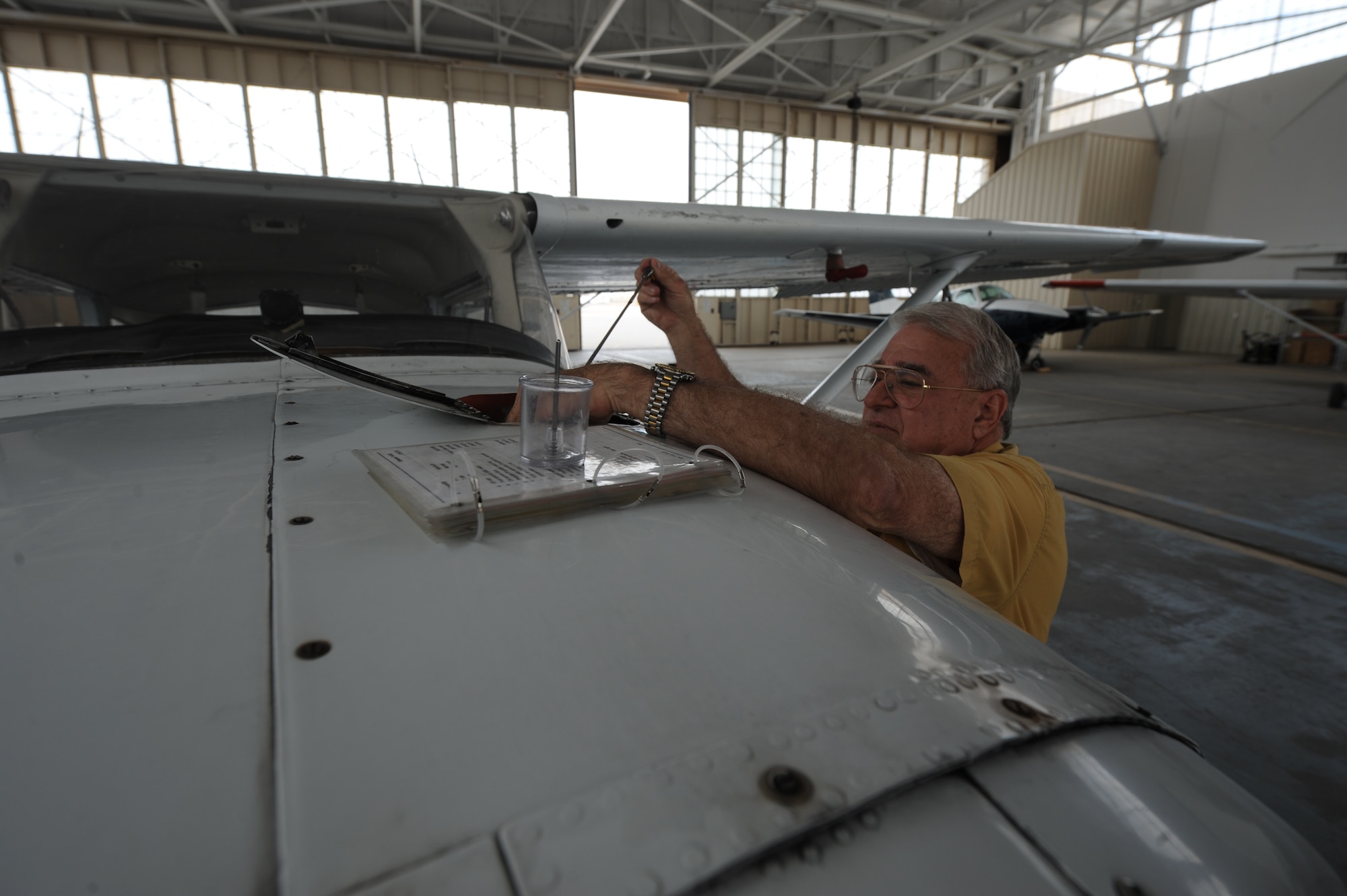 Kirtland Aero Club chief flight instructor Jon Daffer checks the oil on a trainer aircraft during the required preflight inspection. 