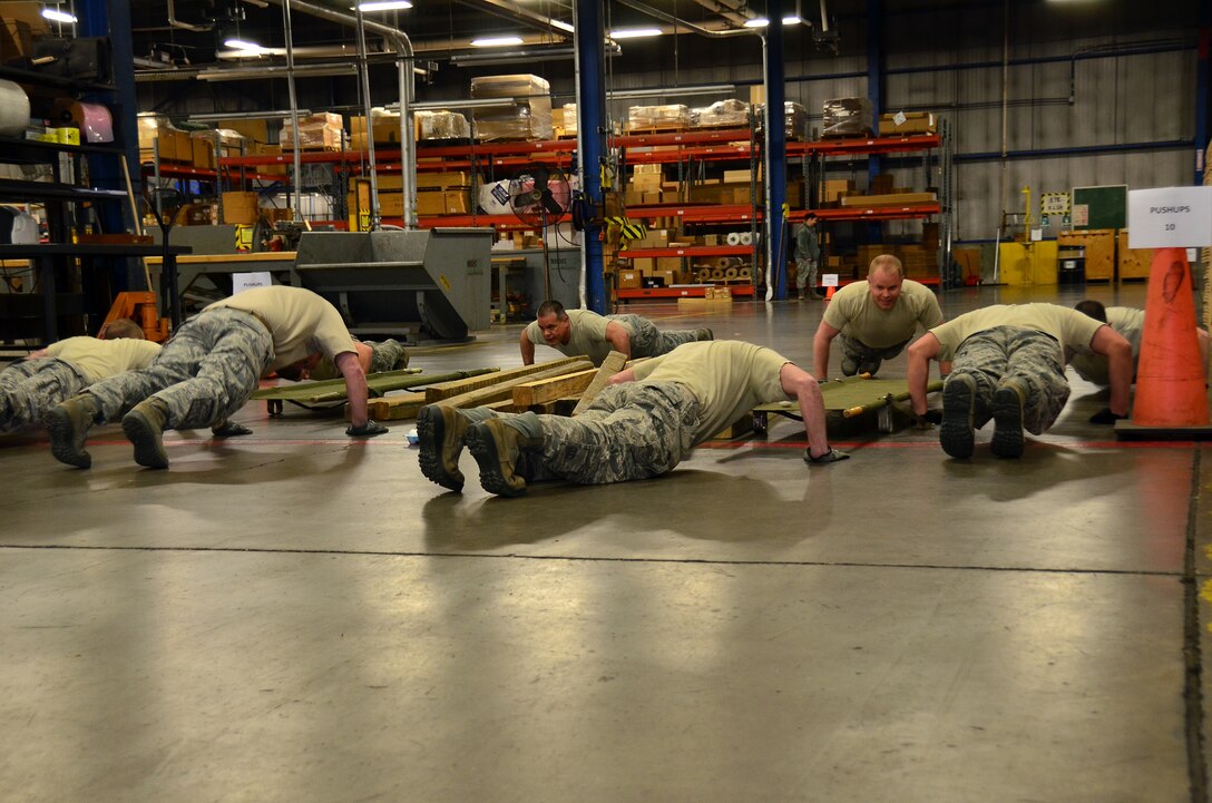 WRIGHT-PATTERSON AIR FORCE BASE, Ohio - Two teams race against the clock to complete the 87th Aerial Port Squadron team building challenge that included push-ups, carrying a litter of planks followed by executing 25 jumping jacks, then exchanging the planks for an egg before crossing the finish line without dropping it. The challenge was part of the 445th Airlift Wing annual Wingman Day held during the April 21 unit training assembly. (U.S. Air Force photo/Staff Sgt. Amanda Duncan)