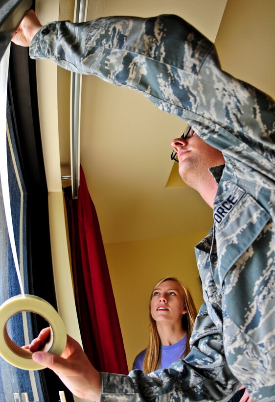 Airman 1st Class Taylor Neuharth, 36th Civil Engineer Squadron Emergency Management Flight apprentice, shows a base resident how to use tape on the windows in her home May 30, 2013, on Andersen Air Force Base, Guam, to make them shatter resistant. The emergency management flight’s mission is to lead base preparation, response and recovery from all types of hazards, disasters and catastrophes. (U.S. Air Force photo by Airman 1st Class Marianique Santos/Released)