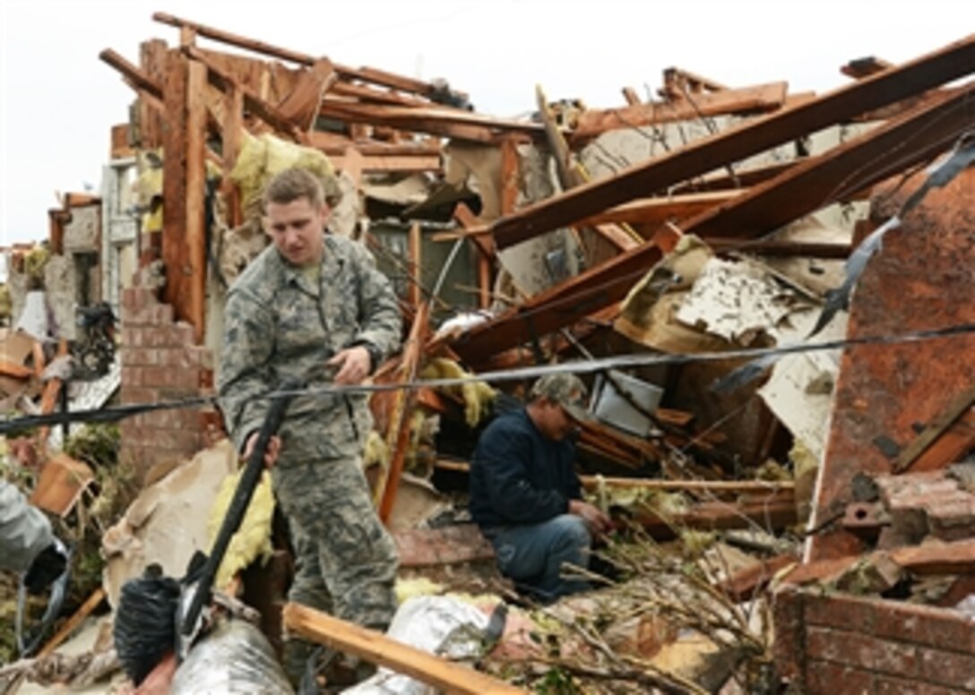 Senior Airman Joshua Jacobs helps a resident recover personal property from his demolished house during recovery operations in Moore, Okla., on May 21, 2013.   A massive tornado hit the area on May 20 leaving leveled houses, businesses and schools in its wake.  Jacobs is attached to the 146th Air Support Operations Squadron.  