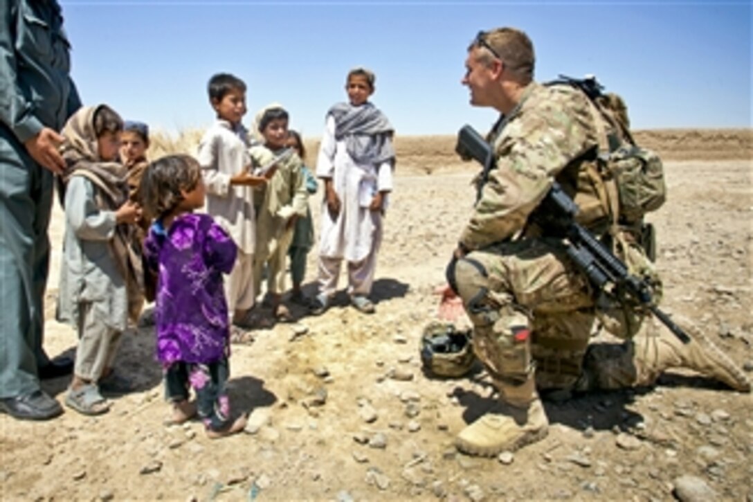 U.S. Army Staff Sgt. Matthew Parsons talks with Afghan children during a partnered operation with Civil Order Police in Delaram in the Helmand province of Afghanistan, on May 26, 2013.  Parsons is attached to the Police Advisor Team Delaram as an instructor and mentor for their Civil Order Police counterparts.  