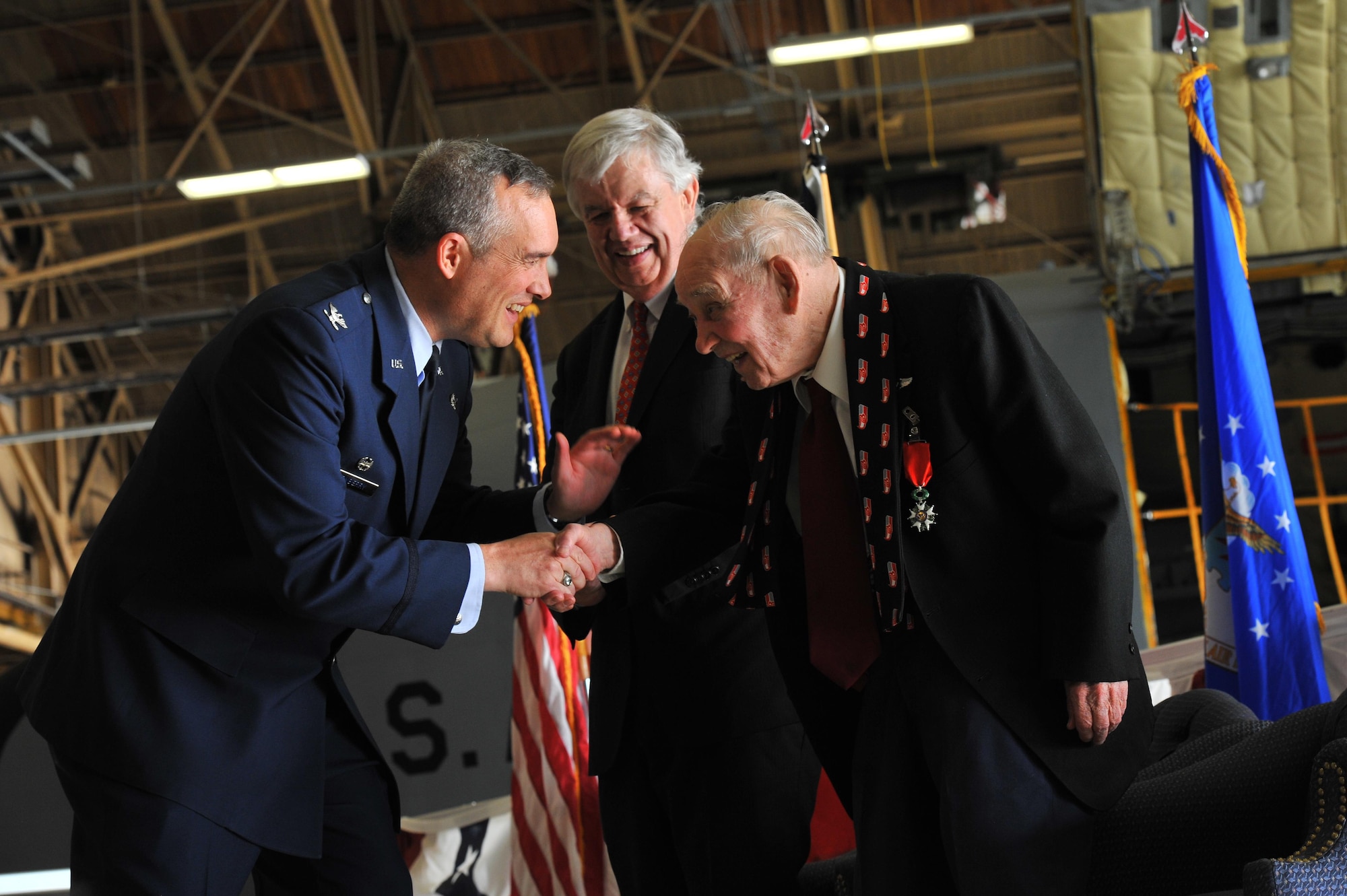 Col. Brian Newberry congratulates retired Maj. Clarence Grimes Oct. 25, 2013, at Fairchild Air Force Base, Wash., while Jack Cowan, Honorary Consul of France, gathers with them. The 92-year old was honored with the highest recognition by the French government for his contributions almost 70 years ago to defend and preserve the independence of France. Newberry is the 92nd Air Refueling Wing commander. 