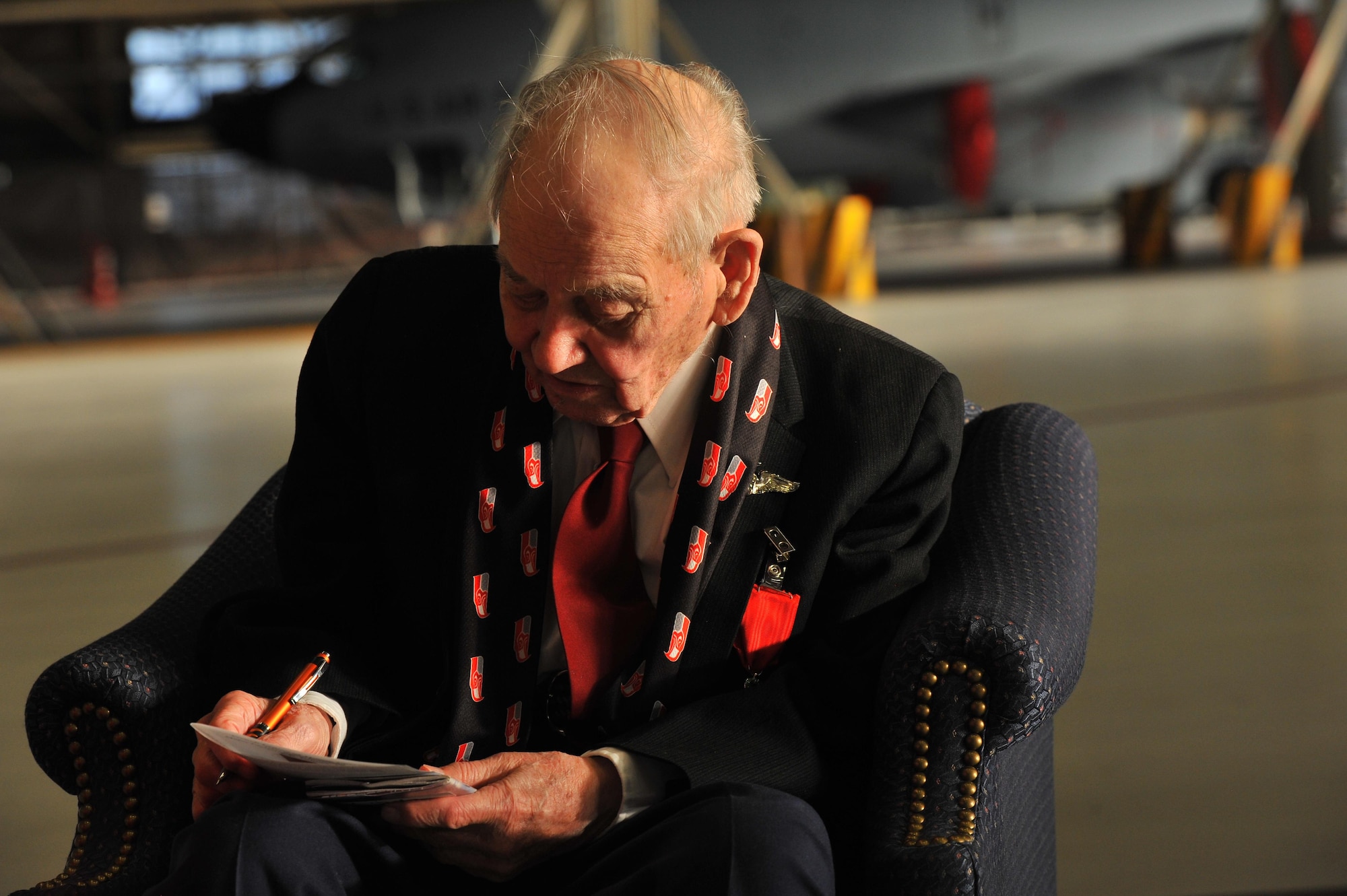 Retired Maj. Clarence Grimes signs an autograph after receiving the French Legion of Honor Medal Oct. 25, 2013, at Fairchild Air Force Base, Wash. Grimes was honored with the highest recognition by the French government for his contributions almost 70 years ago to defend and preserve the independence of France. 