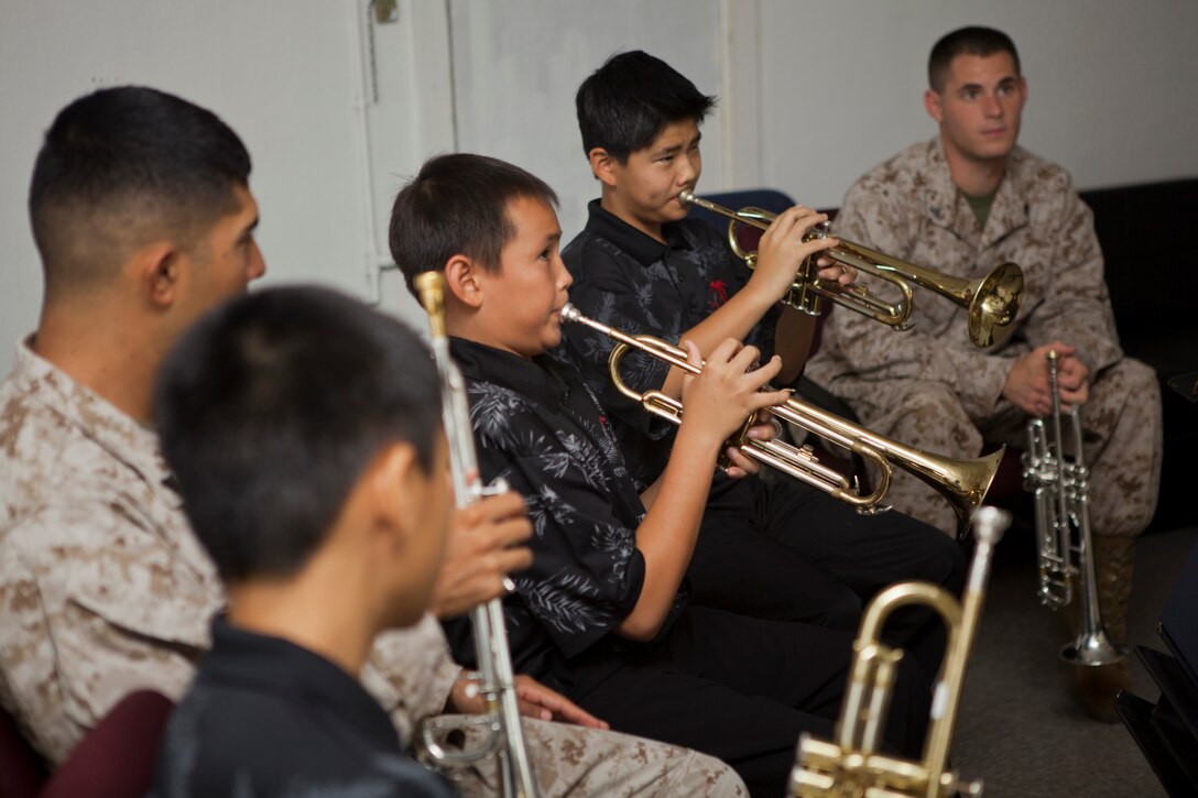 A pair of students with the Intermediate Band from Iolani School play the trumpet as Marines from the U.S. Marine Corps Forces, Pacific Band observe in the band's hall aboard Marine Corps Base Hawaii, Oct. 30, 2013. The band students received the opportunity to work one-on-one with the Marines and learn new techniques to increase their performance with their instruments.