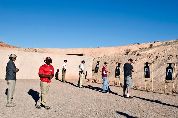 Participants of the Nevada concealed weapons course prepare to fire while Staff Sgt. Cory Green, 99th Security Forces Squadron combat arms training and maintenance instructor, and Tech. Sgt. Ramone Jenkins, 820th RED HORSE combat arms training and maintenance instructor, oversees the firing line Oct. 26, 2013, at Nellis Air Force Base, Nev. After attending an eight hour classroom portion of the training, applicants must score 21 out of 30 firing at three, five and seven meter targets. (U.S. Air Force photo by Senior Airman Matthew Lancaster)