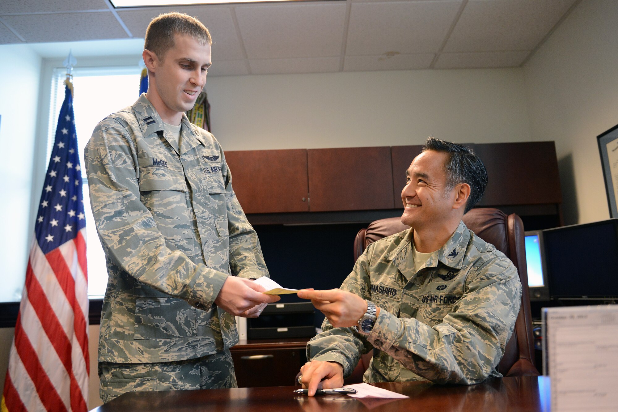 Col. David Kumashiro, 62nd Airlift Wing commander, hands Capt. Theo McGee, Team McChord’s community assistance project officer for Combined Federal Campaign, his pledge form Oct. 30, 2013, at Joint Base Lewis McChord. Team McChord resumed its Combined Federal Campaign drive Oct. 1, following the government shutdown which suspended the campaign for five days. (U.S. Air Force photo/Airman 1st Class Jacob Jimenez)    