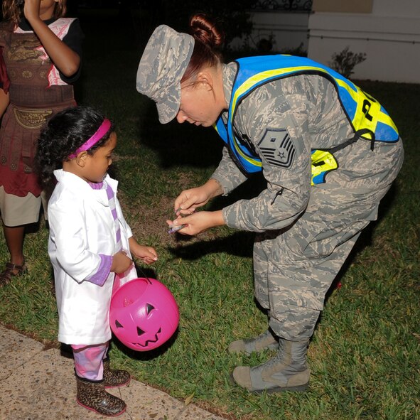 Master Sgt. Christina Hernandez, 2nd Aircraft Maintenance Squadron first sergeant, wraps a glow-stick around a child?s wrist on Barksdale Air Force Base, La., Oct. 31, 2013. Volunteers escorted families and passed out glow-sticks for safety during trick-or-treating hours. (U.S. Air Force photo/Senior Airman Kristin High)