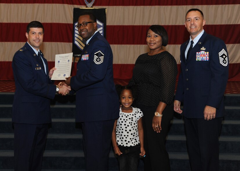 Master Sgt. Lasabra Johnson, 2nd Bomb Wing personnel reliability program, receives a certificate of promotion from Col. Andrew Gebara, 2nd BW commander, and Chief Master Sgt. Curtis Storms, 2nd BW command chief, during the October Wing Promotion Ceremony on Barksdale Air Force Base, La., Oct. 31, 2013. (U.S. Air Force photo/Senior Airman Joseph A. Pagán Jr.)