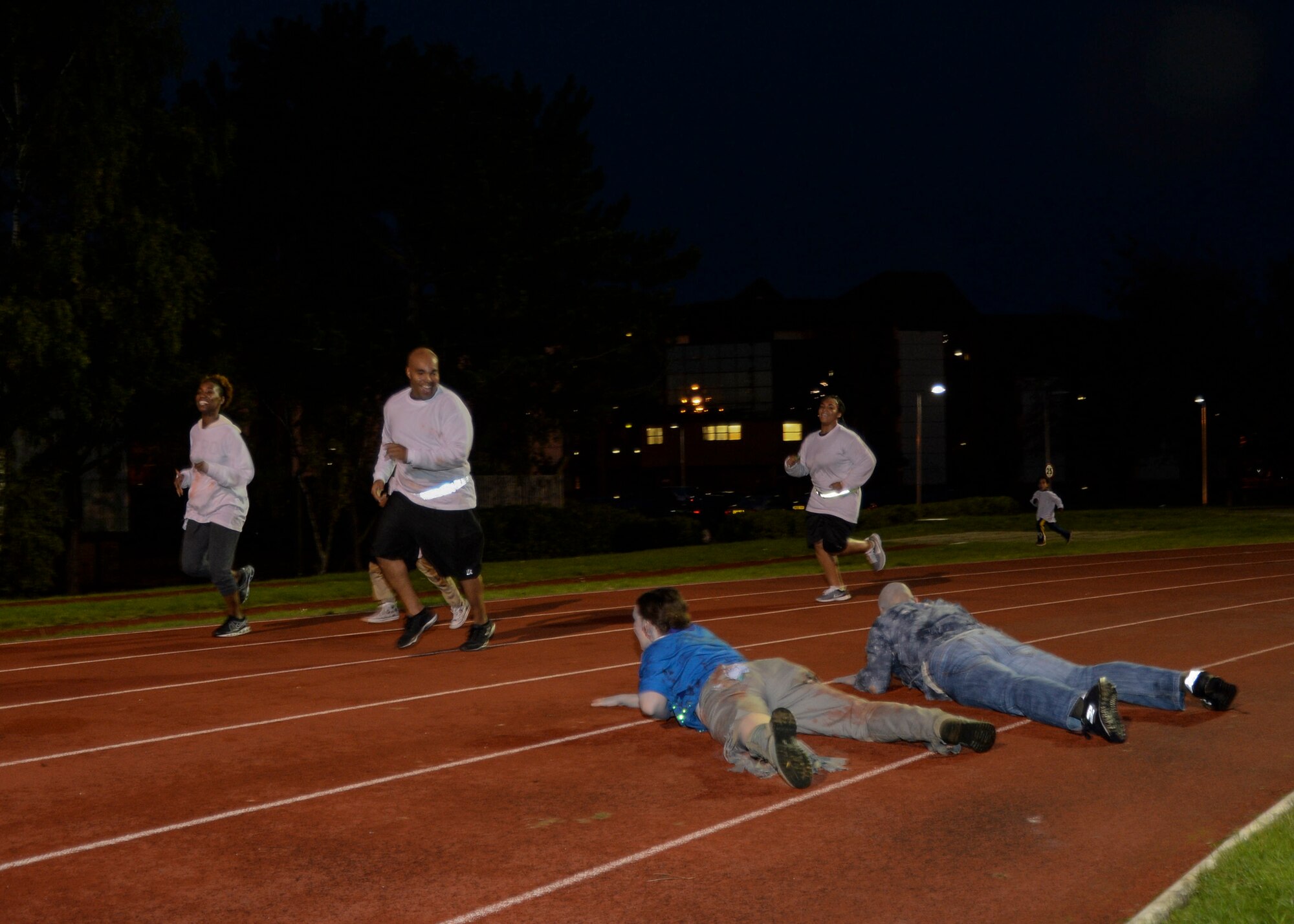 Zombies crawl towards Halloween Zombie Run participants finishing the course at the base track on Royal Air Force Lakenheath, England, Oct. 31, 2013. Runners participated in a 30-minute course around the installation while evading “get ya” zombies blocking their paths. (U.S. Air Force photo by Airman 1st Class Nigel Sandridge/Released)