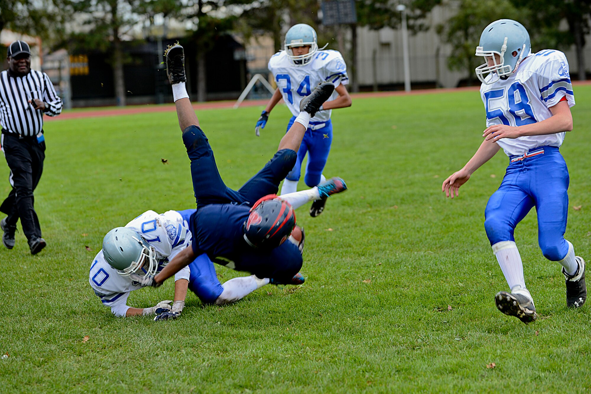 Donte Hall (blue), Lakenheath High School Junior Varsity Lancers running back flips over a Brussels American School football team member during a game at the Royal Air Force Lakenheath, England, football field Oct. 26, 2013. Hall rushed six times for 48 yards in their 42-0 loss. (U.S. Air Force photo by Airman 1st Class Trevor T. McBride/Released)