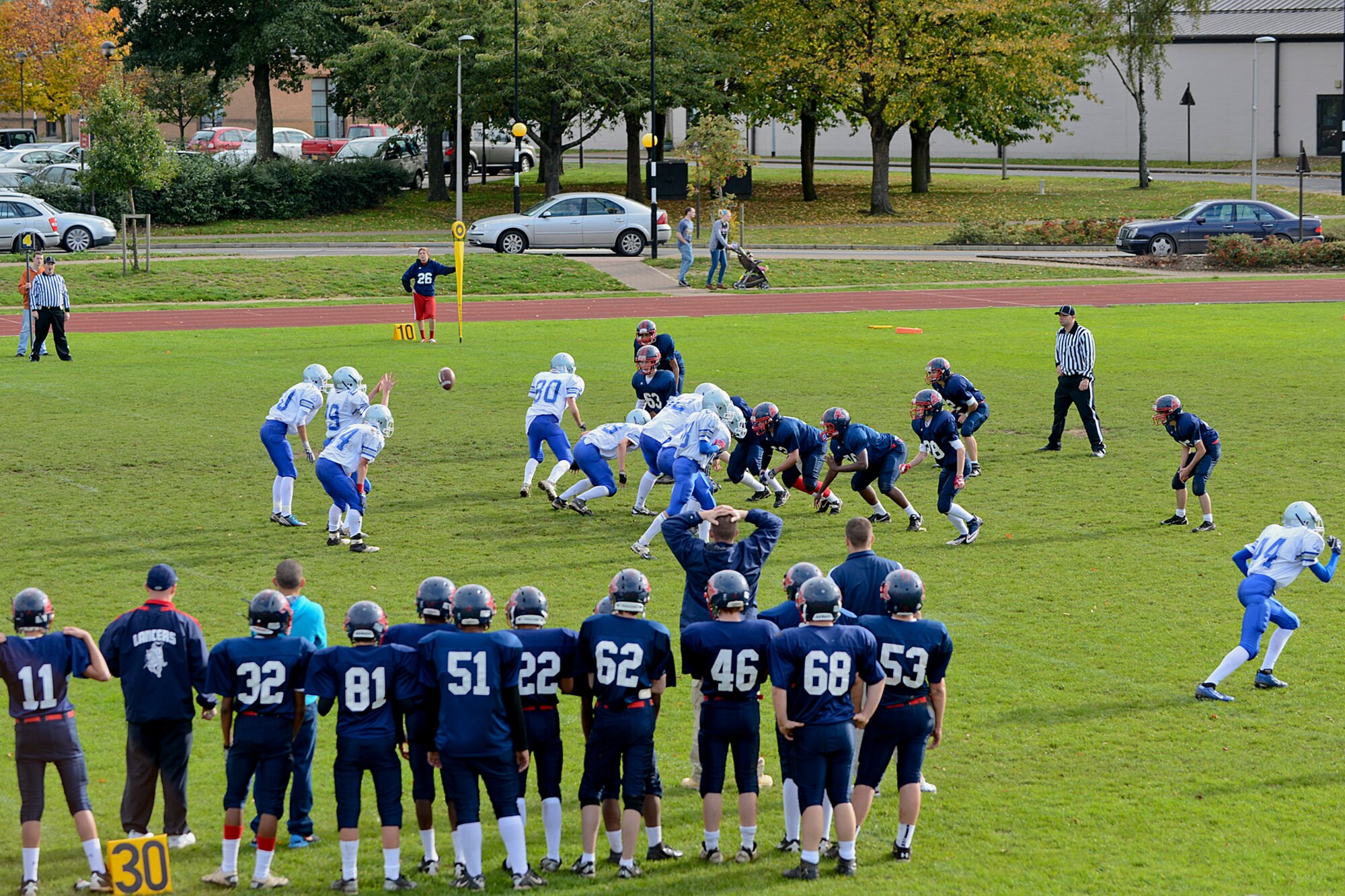 Brussels American School football team (white) runs an offensive play against the Lakenheath High School Junior Varsity Lancers at the Royal Air Force Lakenheath, England, football field Oct. 26, 2013. The Lancers lost 42-0 but look forward to a more successful 2014 football season.  (U.S. Air Force photo by Airman 1st Class Trevor T. McBride/Released)