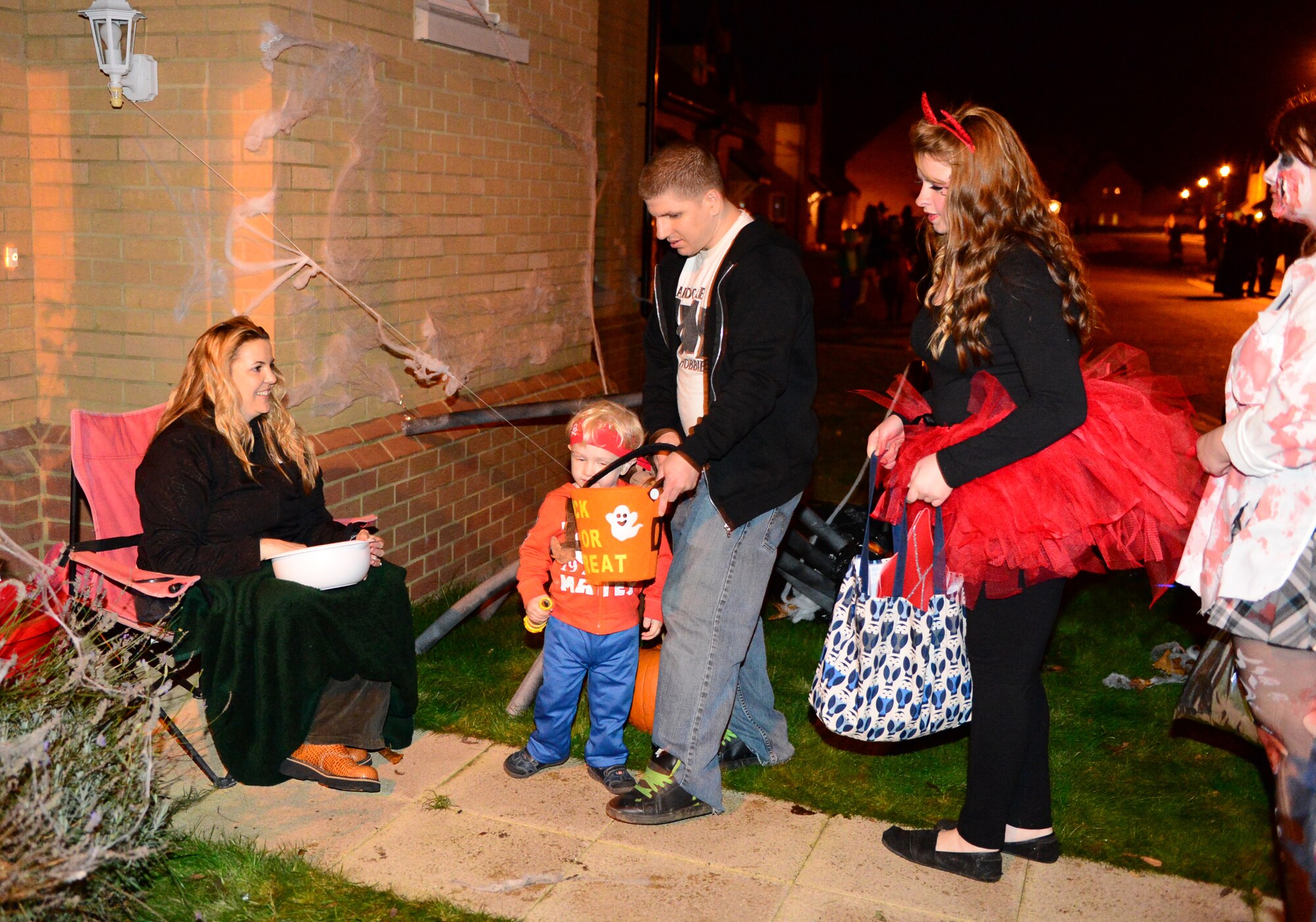 Elizabeth Dufault, wife of Staff Sgt. Joseph Dufault, 56th Rescue Squadron aircrew flight equipment, greets trick-or-treaters on Royal Air Force Lakenheath, England, Oct. 31, 2013. Residents of Liberty Village opened their doors to parents and children to promote a safe Halloween. (U.S. Air Force photo by Airman 1st Class Dawn M. Weber/Released)