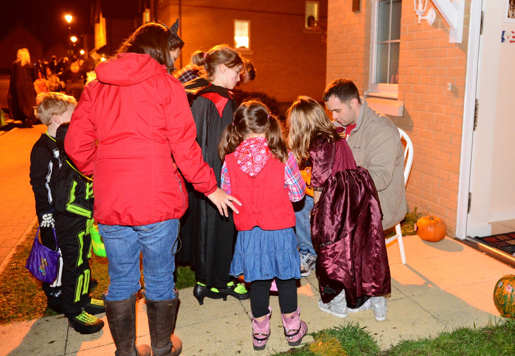 Tech. Sgt. Brian Bunch, 100th Aircraft Maintenance Squadron communication and navigation specialist, passes out candy to trick-or-treaters on Royal Air Force Lakenheath, England, Oct. 31, 2013. Residents of Liberty Village opened their doors to parents and children to promote a safe Halloween. (U.S. Air Force photo by Airman 1st Class Dawn M. Weber/Released)