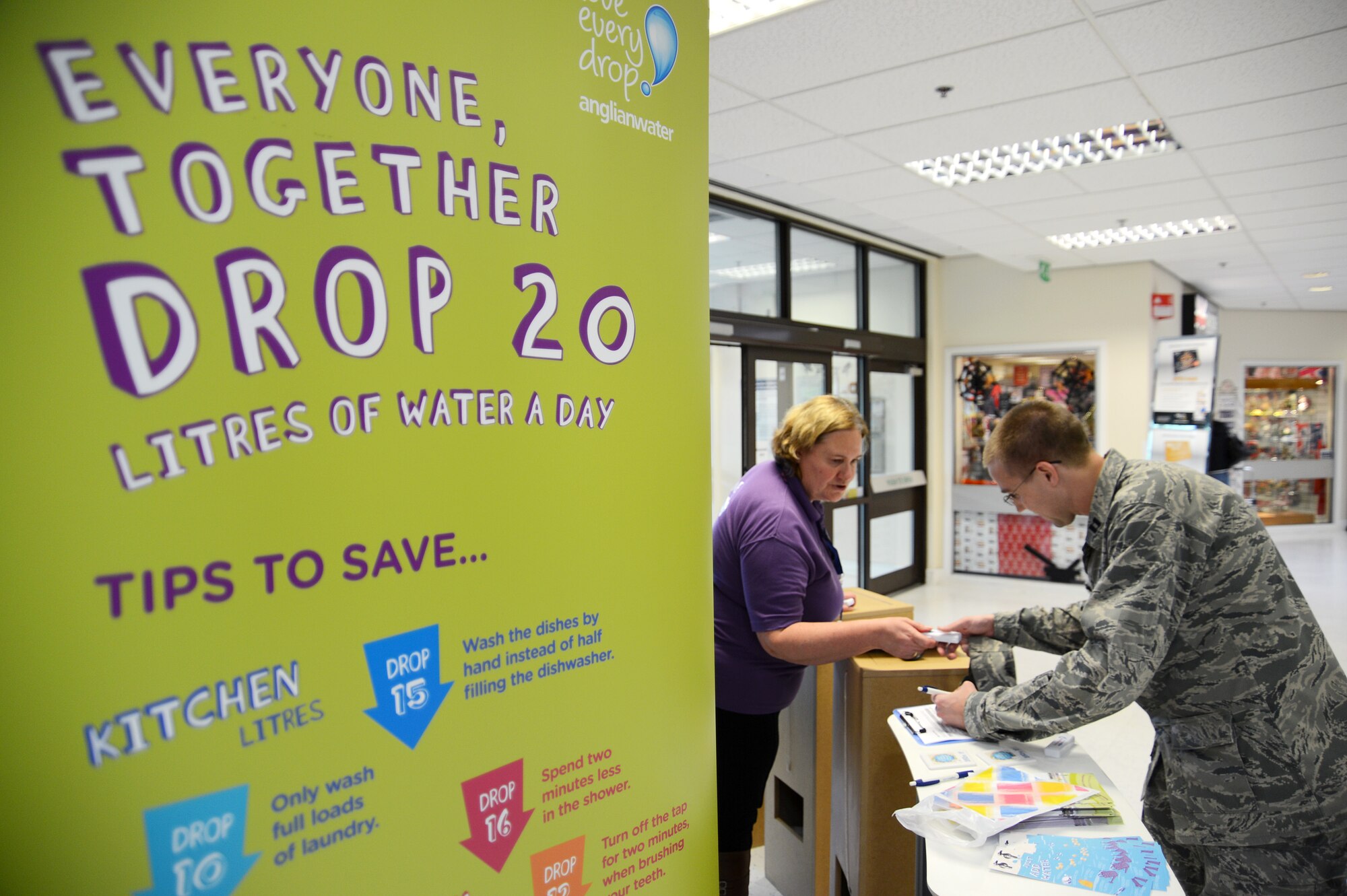 Christine Buchan, Anglian Water representative, helps Capt. David Sayers, 48th Medical Operations Squadron pediatrician, register for a prize drawing at the Royal Air Force Lakenheath, England, Exchange Oct. 24, 2013. Anglian Water, which provides services for RAFs Lakenheath, Feltwell and Mildenhall, hosted the information booth on water conservation as part of the base’s Energy Action Month activities. “It may seem strange that as a company we’re asking people to use less water, but in the end it benefits everyone by saving resources and money,” said Buchan. “If I can get one person to turn off the tap while brushing their teeth, then job done.” (U.S. Air Force photo by Staff Sgt. Thomas Trower/Released)