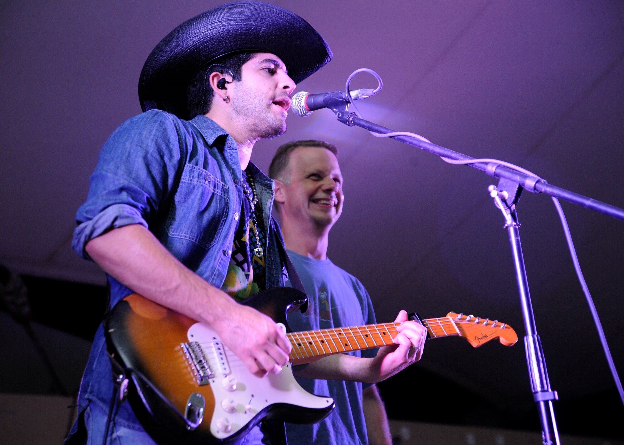 Charles Longoria, a “Lost Trailers” guitarist and band leader, sings alongside Col. Gregory DeWolf during a concert at the 379th Air Expeditionary Wing in Southwest Asia, Oct. 31, 2013. 379th AEW leaders were invited to join the American country band during their performance. DeWolf is the 379th Expeditionary Medical Group commander here on a one-year rotation and a Cedar Rapids, Iowa, native. (U.S. Air Force photo/Senior Airman Bahja J. Jones) 